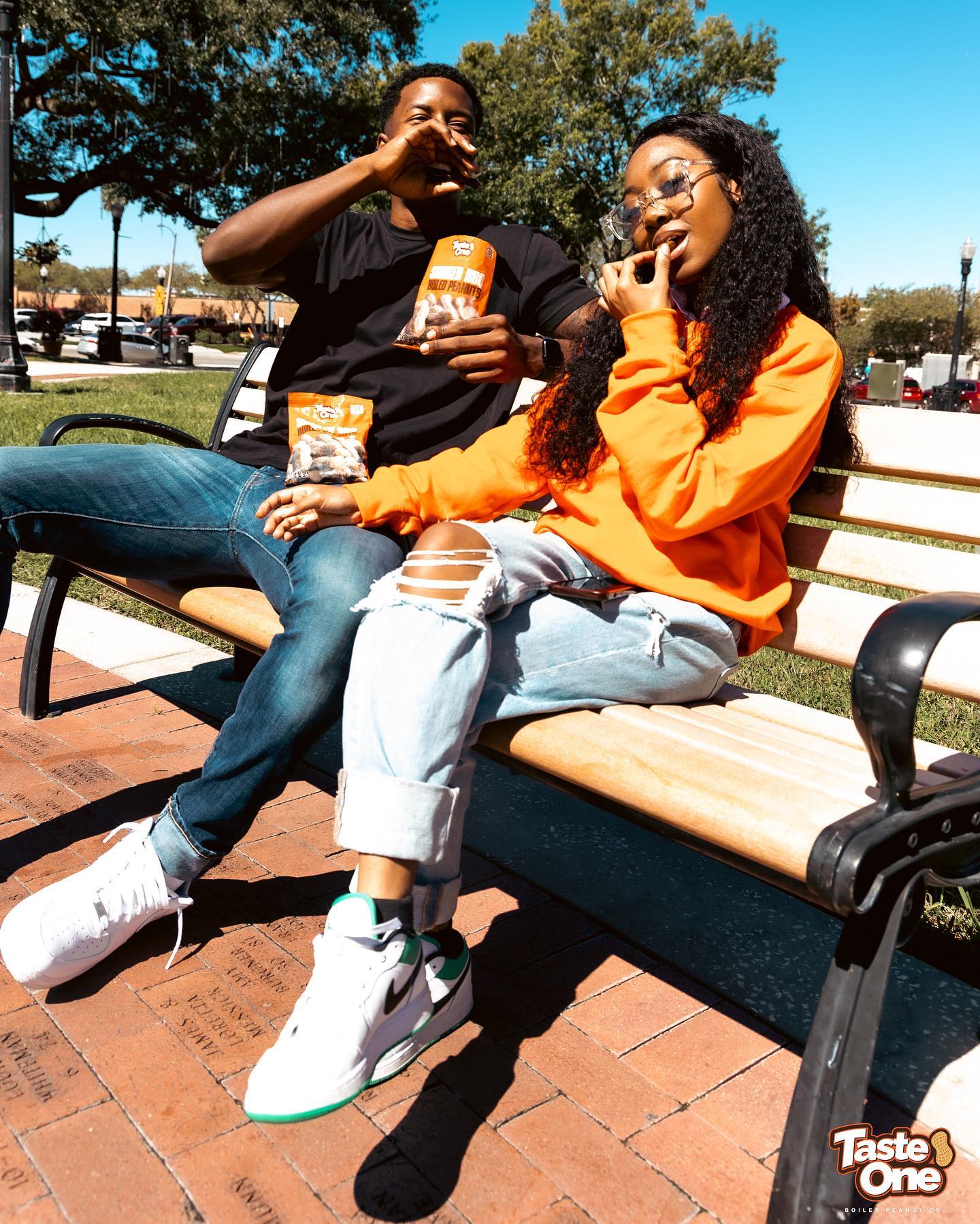 Two fans sharing a bag of Taste One boiled peanuts on a bench